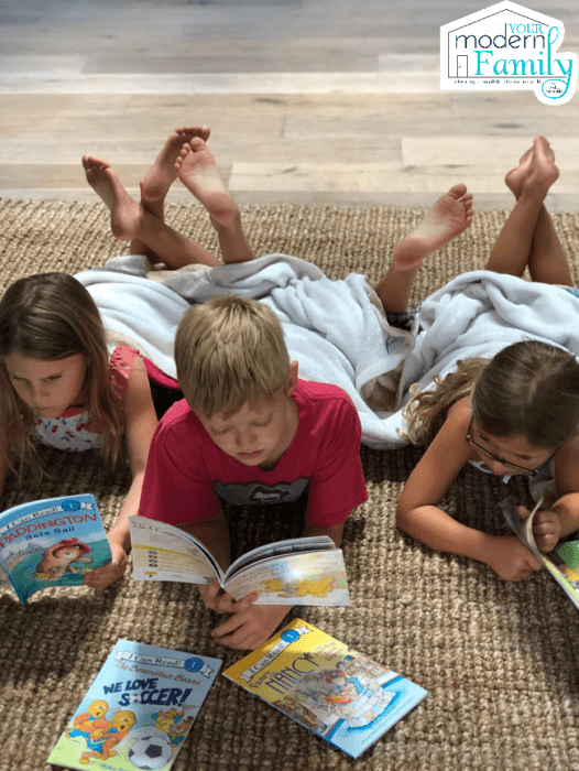 A group of children lying on the floor reading books.