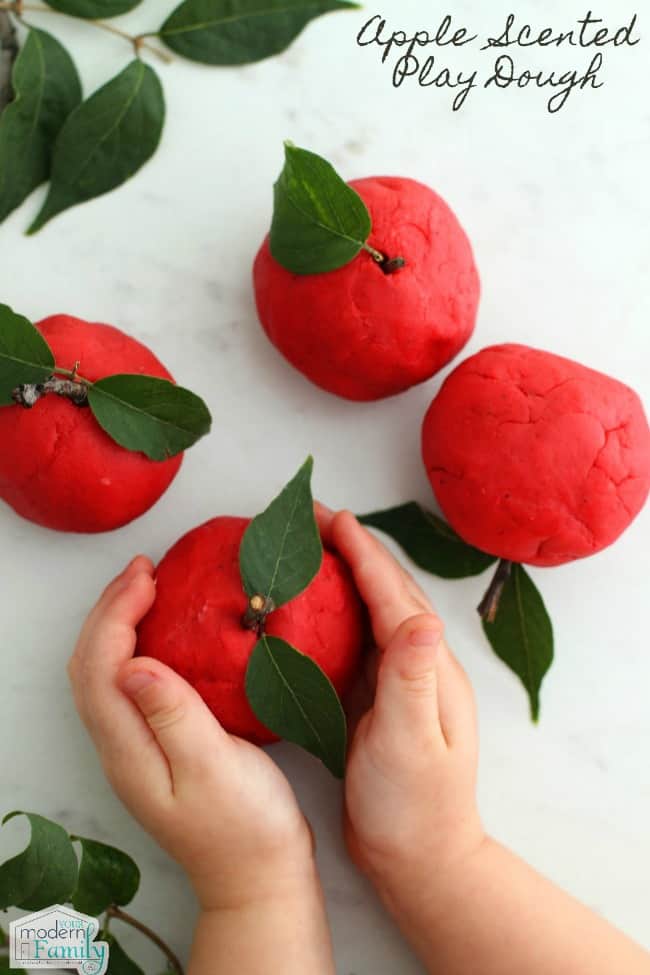 A close up of a hands holding red play dough apple craft.