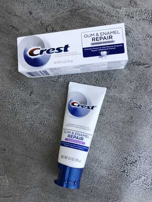 A tube of Crest and it's box sitting on a counter.