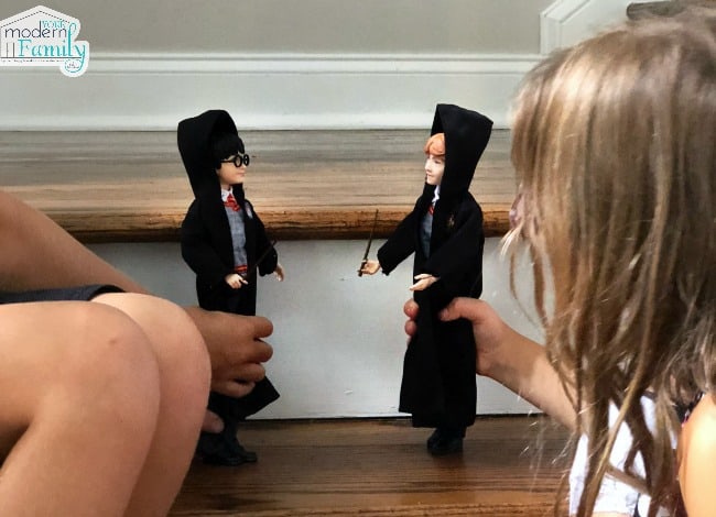 Two children playing with  Harry Potter and  Hermione Granger figurines.