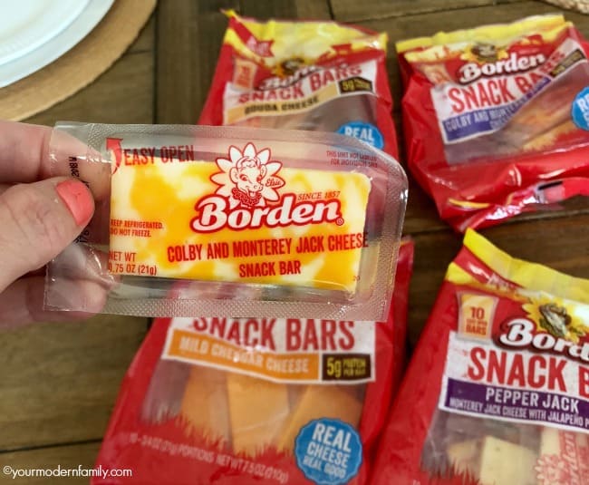 A variety of different bags of Borden cheesy snack bars on a table.
