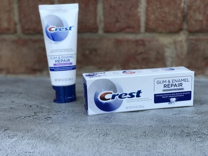 A tube and box of Crest repair tooth paste sitting on a cement step.