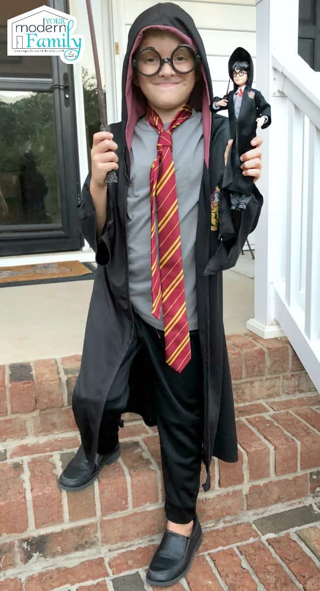 A small boy standing on brick steps dressed up as Harry Potter.