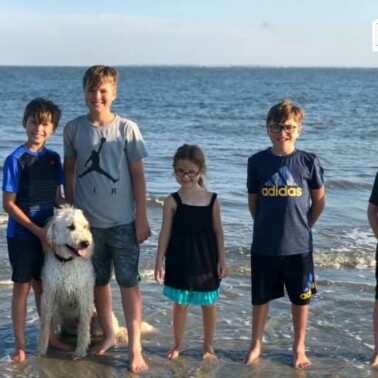 A group of people standing on a beach with a dog.