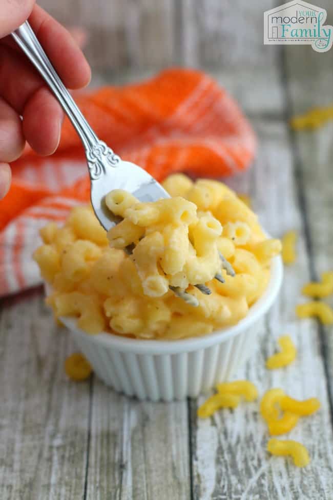 A small white bowl with macaroni and cheese in it with a fork.