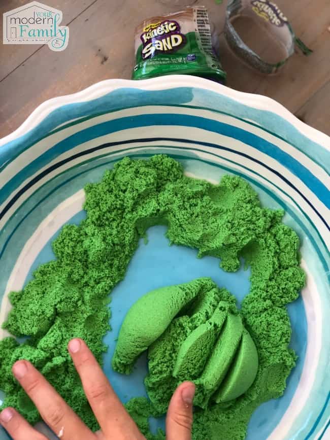 Green Kinetic sand on a blue and white plate.