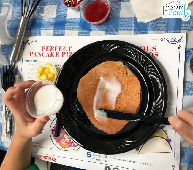 A person adding butter onto a pancake.