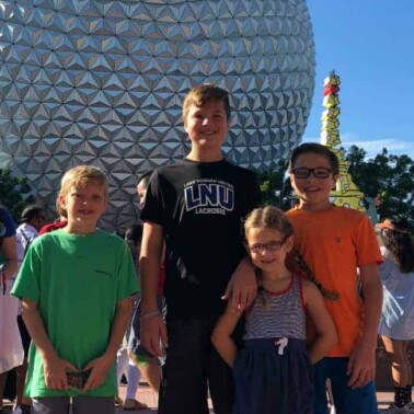 A group of people posing for the camera in front of the Epcot ball.