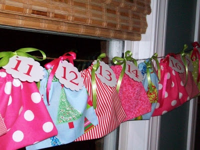 A clothes line with decorative cloth material hanging with ribbons holding numbers to count down to Christmas.