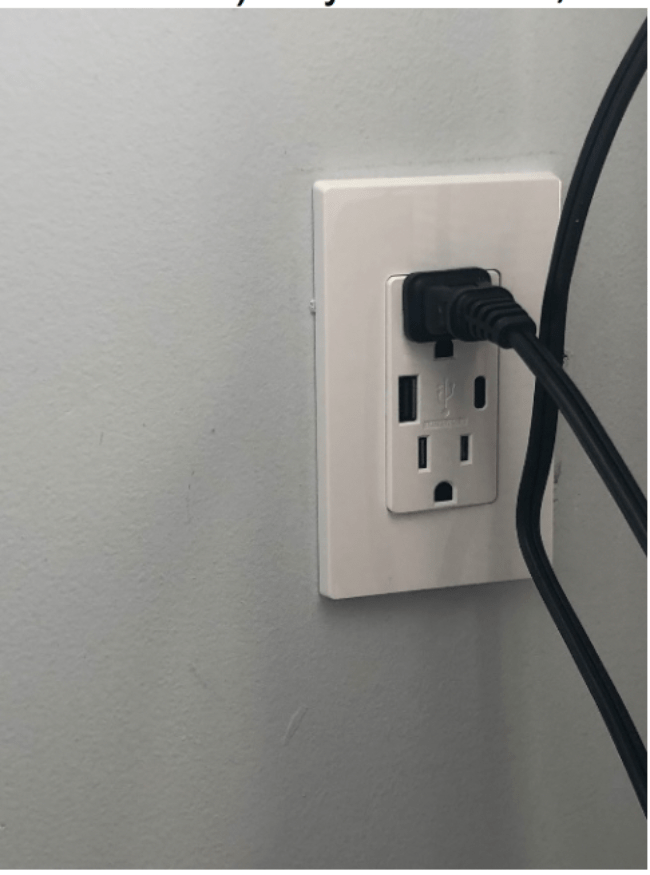 A black electrical cord plugged into a wall outlet.