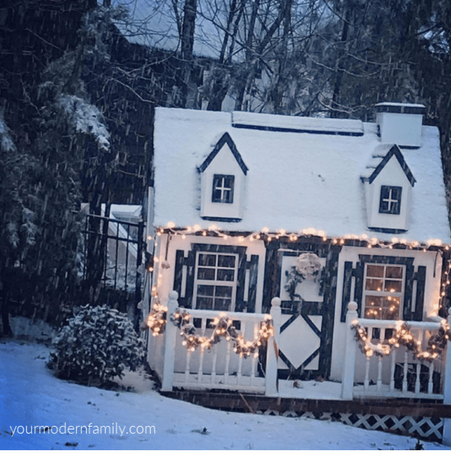 A playhouse decorated with Christmas lights covered in snow.