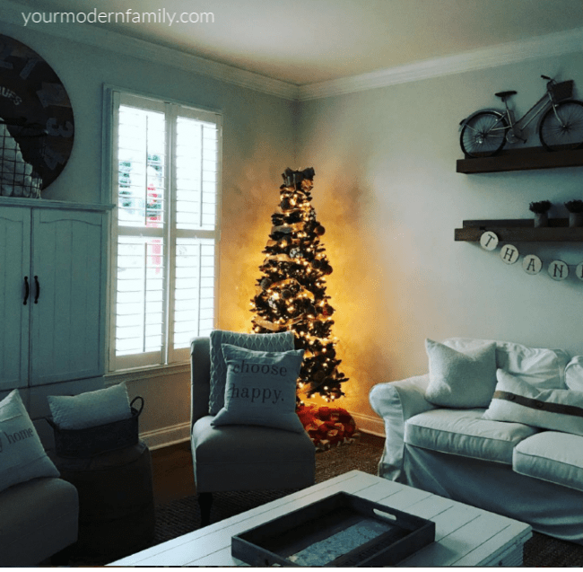 A living room filled with furniture and a large window and a Christmas tree in the far corner.
