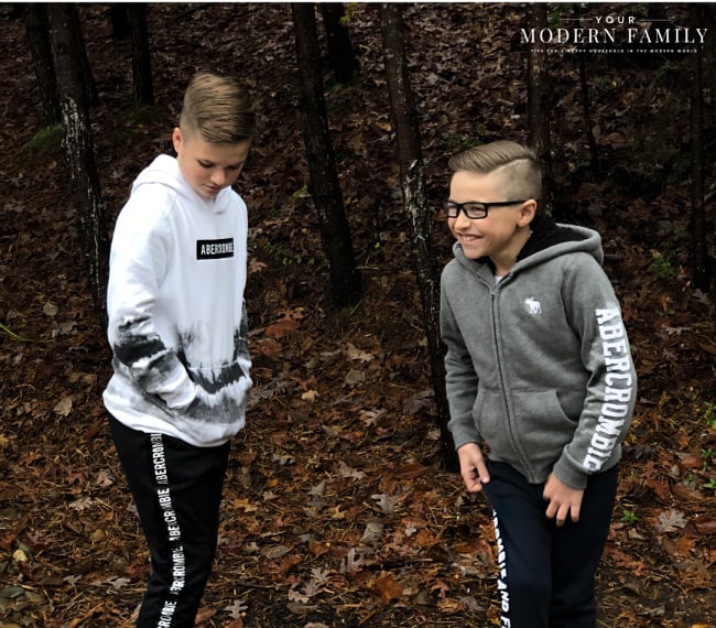 A couple of boys standing near each other with trees in the background.