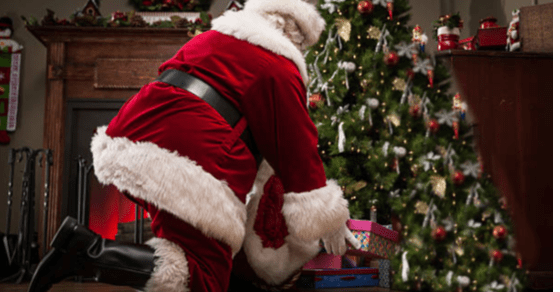  Santa Claus placera gåvor under ett träd.