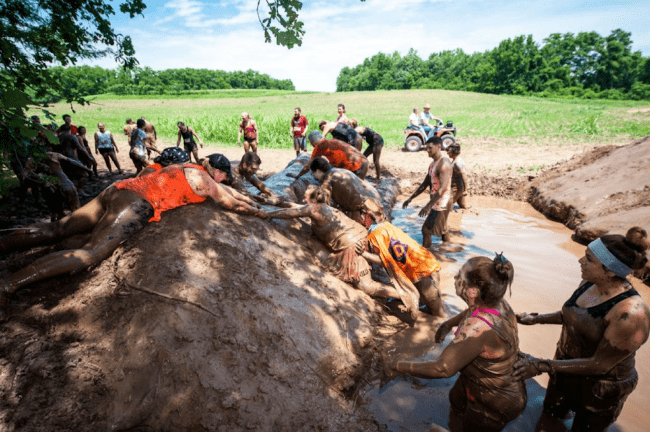 A large group of people climbing over a muddy hill.