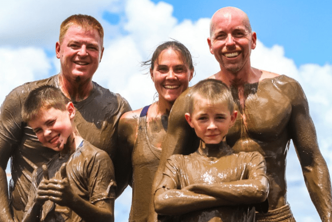 A group of people posing for the camera covered in mud.