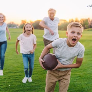 A group of kids and an adult playing football.