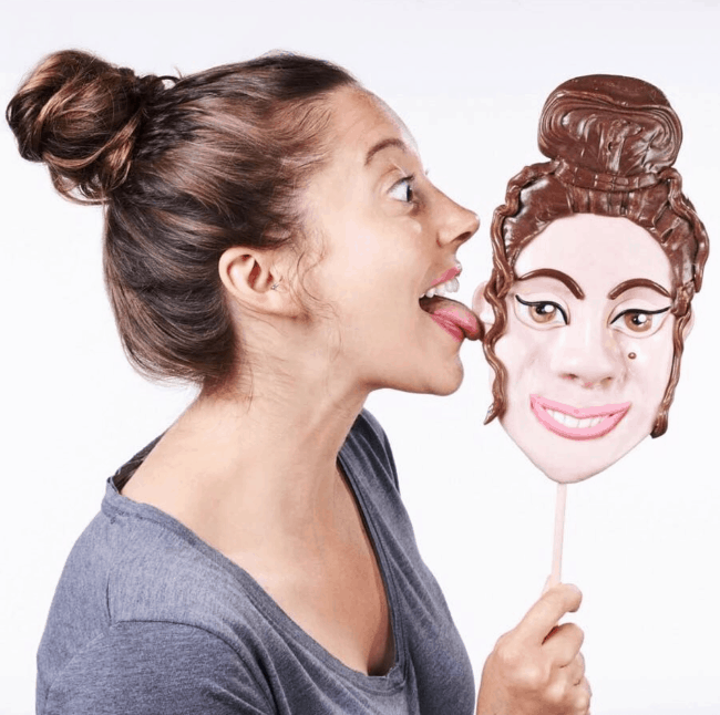 A woman licking a giant lollipop of her face. 