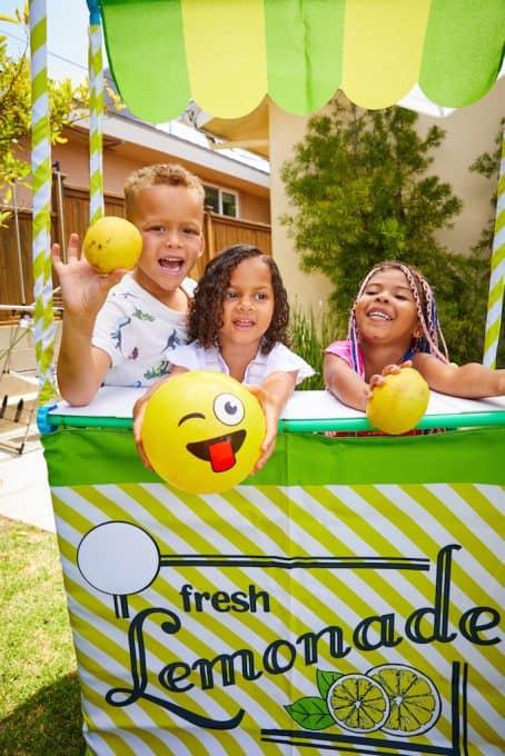 A group of people posing for the camera behind a lemonade stand.