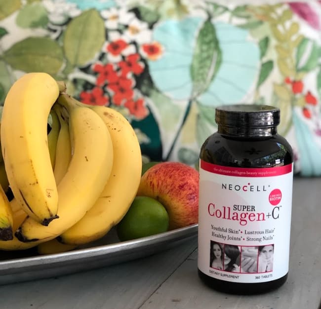 A bottle of Collegen C on a table the a plate of bananas behind it.