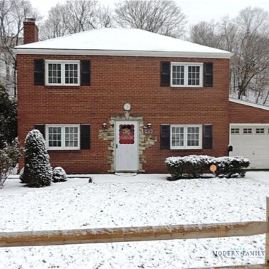 A brick house with a wooden fence in front in the snow.