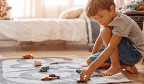 A small child playing cars on the floor.
