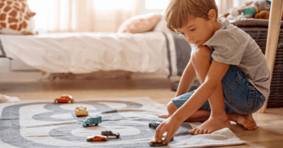 boy playing with cards on a rug in his bedroom