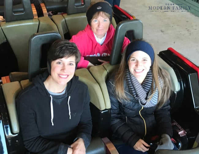 A group of people sitting on seats of a roller coaster.
