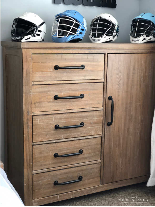 A chest of drawers with sports helmets on it.