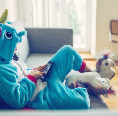 A boy lying on a bed playing on a phone.