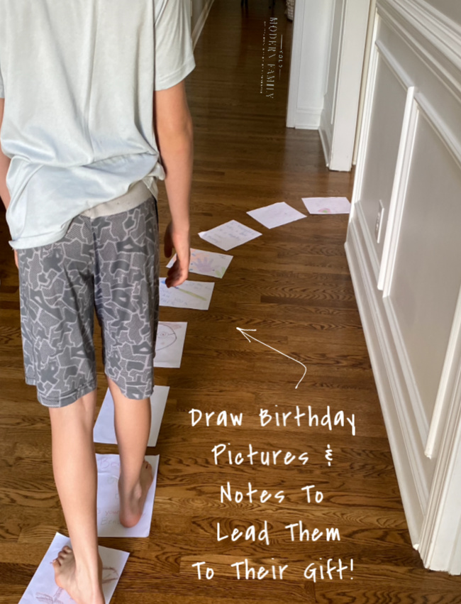 A boy walking down the hall following birthday paper path to his gifts.